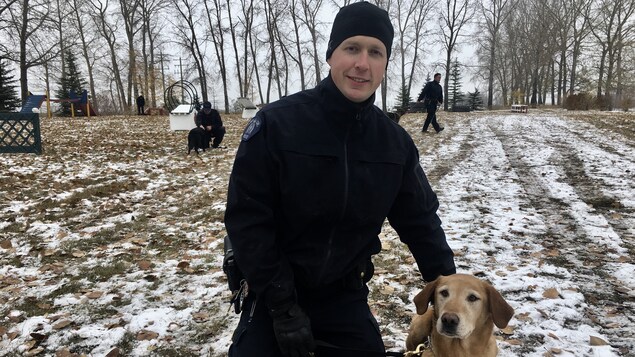Le gendarme Jason Frederick est accroupi dans la neige avec son chien Henry, maintenant retraité. Le gendarme Jason Frederick est accroupi dans la neige avec son chien Henry, maintenant retraité.