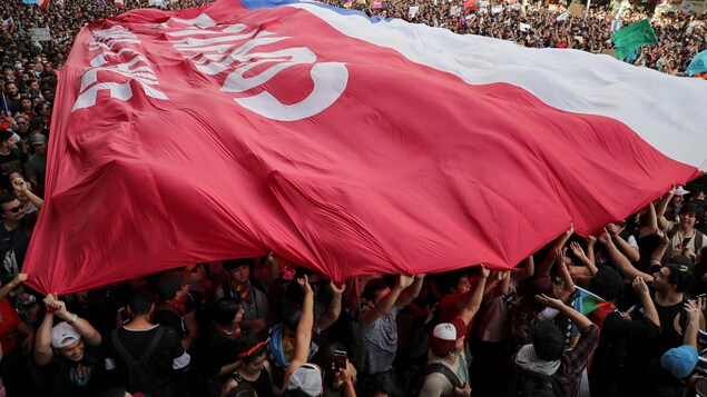 Les manifestants portent un drapeau géant du Chili à Santiago.