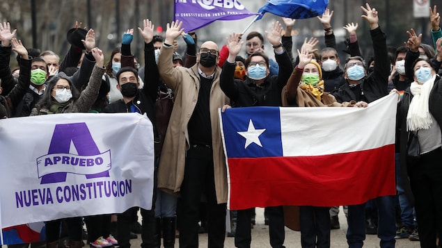 Des gens agitent des drapeaux du Chili et des banderoles en faveur de la nouvelle Constitution.