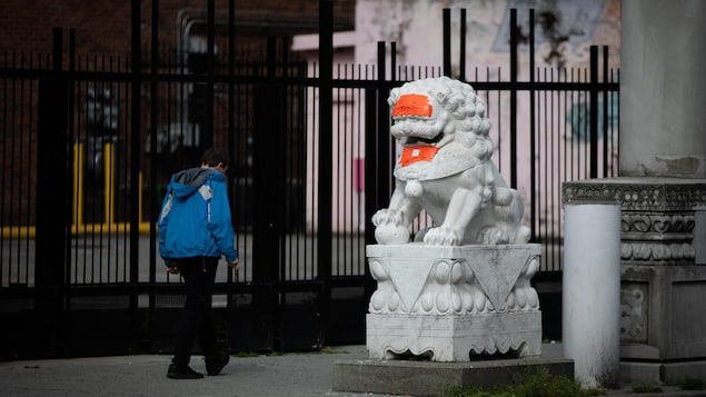 Les statues de lion de la Porte du Millénaire du quartier chinois de Vancouver recouvertes de ruban orange après avoir été dégradées pour la deuxième fois en quelques semaines, le vendredi 29 mai 2020. 