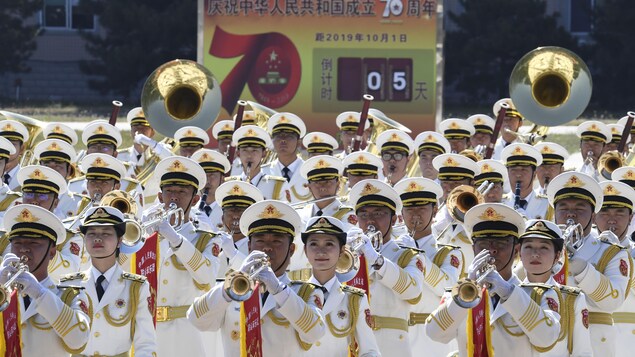 Des membres de la fanfare jouent devant des affiches du 70e anniversaire.