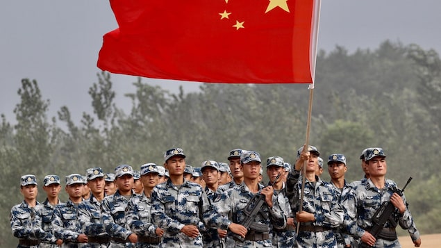 Des soldats brandissent un géant drapeau chinois.