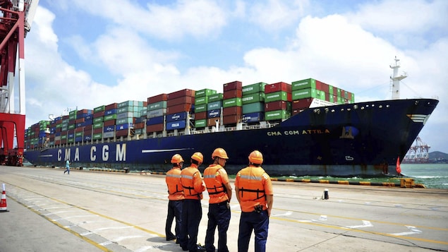 Des débardeurs regardent un bateau sur le quai d'un port chinois.