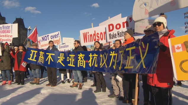 Des membres de la communauté chinoise tiennent une banderole bleue et jaune sur laquelle il est écrit en chinois. Des membres de la communauté chinoise tiennent une banderole bleue et jaune sur laquelle il est écrit en chinois.