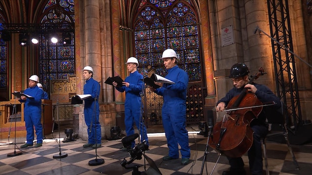 Gautier Capuçon et quatre choristes, qui portent des casques de protection, s'exécutent dans la cathédrale.