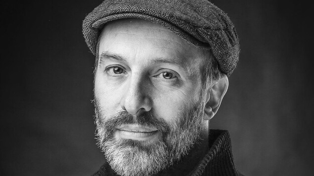 Le comédien et sculpteur Christian Michaud est ravi et étonné du succès de ses oeuvres. Un bel homme, fin quarantaine. Photo en noir et blanc.