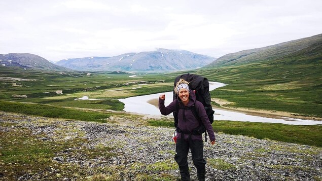 Christine Bérubé-Martin sourit à la caméra, devant des montagnes et des rivières. 