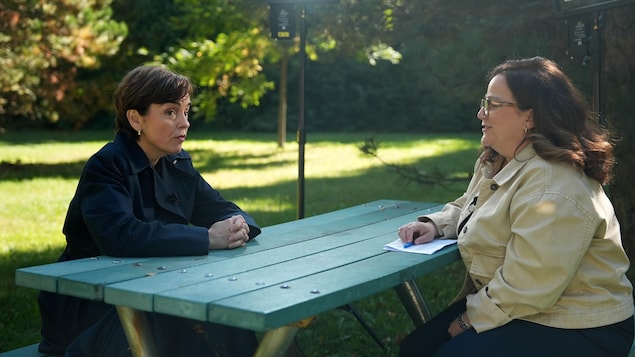 La candidate est assise à une table de pique-nique avec la journaliste, Julie Grenon, dans un parc.