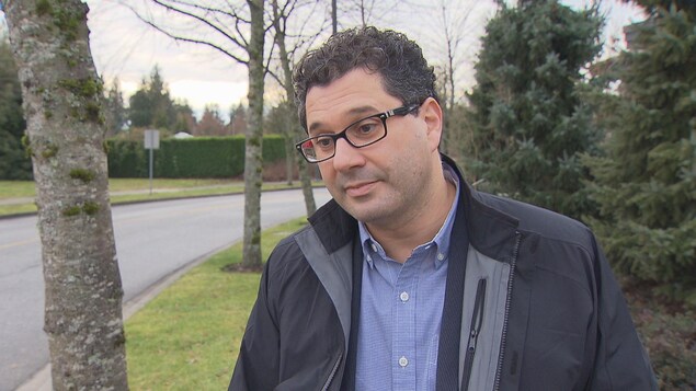 Un homme en entrevue au coin d'une rue, devant des arbres Un homme en entrevue au coin d'une rue, devant des arbres