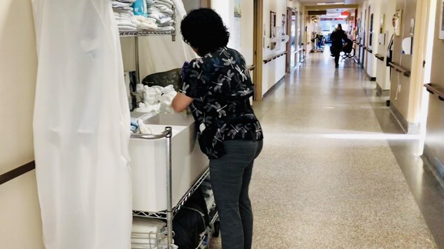 Une femme manipule des serviettes dans le couloir d'un établissement de santé.