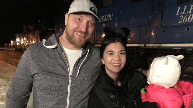Adeelia Spence, résidente de Churchill, avec son compagnon et leur enfant devant un train à l'arrêt dans la nuit. Adeelia Spence, résidente de Churchill, avec son compagnon et leur enfant devant un train à l'arrêt dans la nuit.
