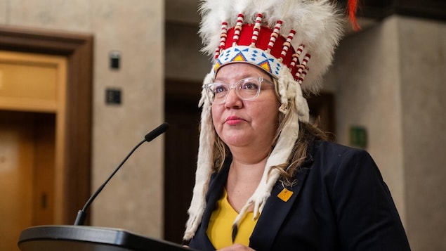 La cheffe nationale de l’APN, Cindy Woodhouse Nepinak portant une coiffe traditionnelle autochtone pendant un discours.