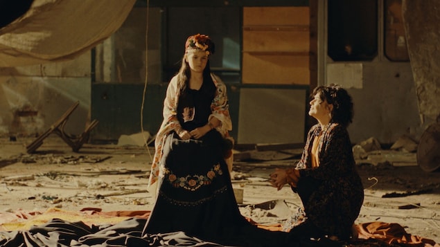 Une jeune fille porte une robe noir aux motifs de fleurs. 