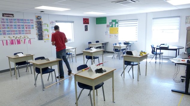Un employé de l'école Saint-François-Xavier s'assure qu'il y a deux mètres entre chaque pupitre.