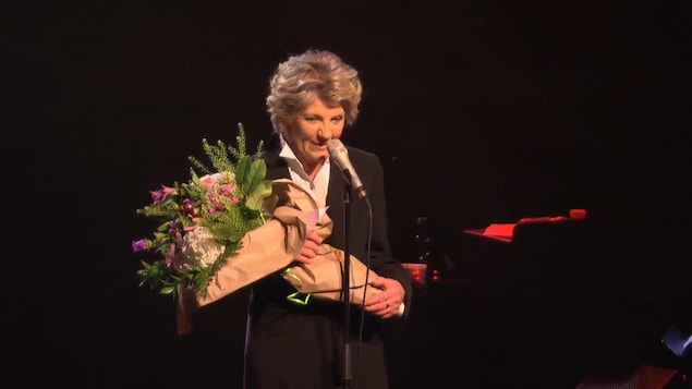 Clémence DesRochers, sur scène, remercie le public avec des fleurs dans les bras. Clémence DesRochers, sur scène, remercie le public avec des fleurs dans les bras.