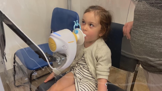 La petite fille souffle dans un appareil.