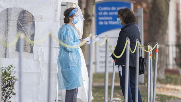 Une travailleuse de la santé parle à une femme dans une clinique de dépistage de COVID-19 à Montréal.