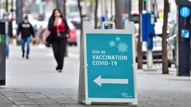 Une affiche indiquant une clinique de vaccination déposée sur le trottoir.