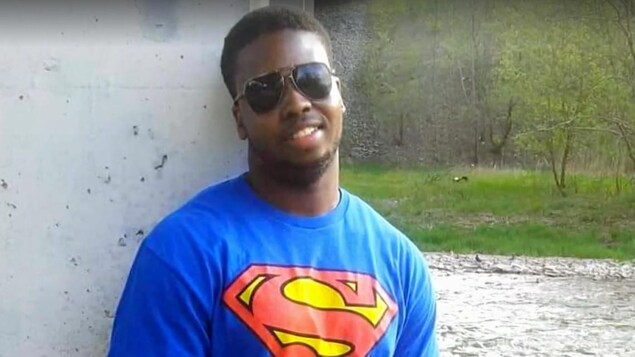 Clive Mensah pose pour la caméra à l'extérieur.