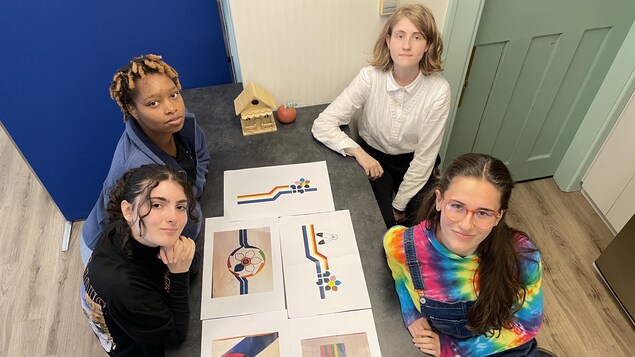 Quatre élèves autour d'une table où sont étalés des prototypes de drapeau.