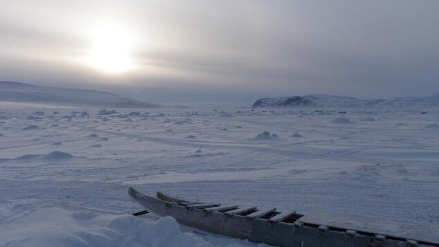 An inuit sled is shown on an icy landscape. 