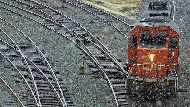 Une locomotive du CN circule sur des rails par temps pluvieux.