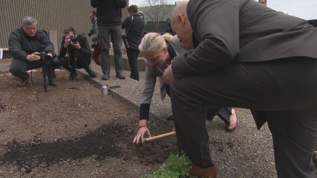 La ministre de l’Environnement et du Changement climatique, Catherine McKenna joue dans la terre sur un toit.