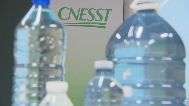 Des bouteilles d'eau devant le logo de la CNESST