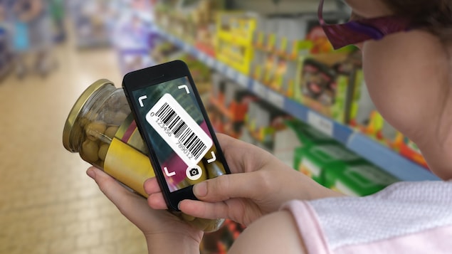Une femme observe un code-barres sur un produit d'épicerie.