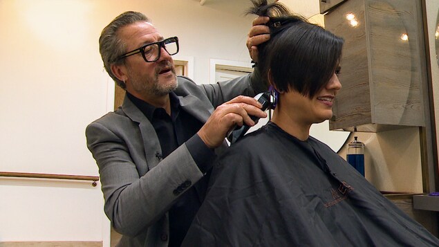 Un coiffeur qui fait une coupe de cheveux à une cliente.