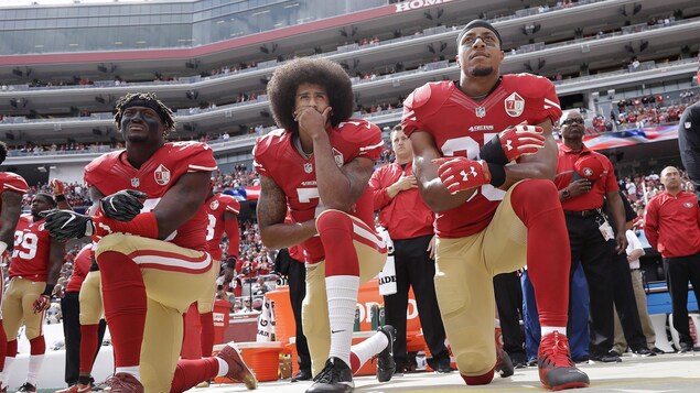 Colin Kaepernick et deux autres joueurs de football agenouillés