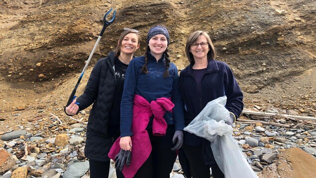 Trois femmes qui ramassent des déchets sur une plage.