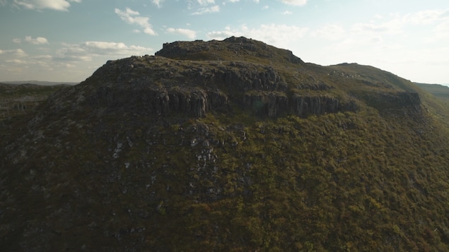 On voit du haut des airs une colline rocheuse arrondie recouverte d'une végétation au ras du sol On voit du haut des airs une colline rocheuse arrondie recouverte d'une végétation au ras du sol