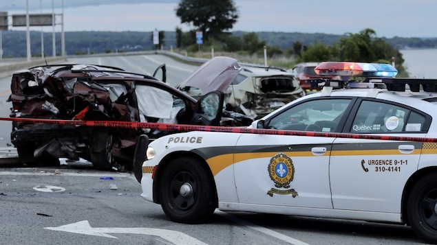 Un véhicules très accidenté et une voiture de la Sûreté du Québec.