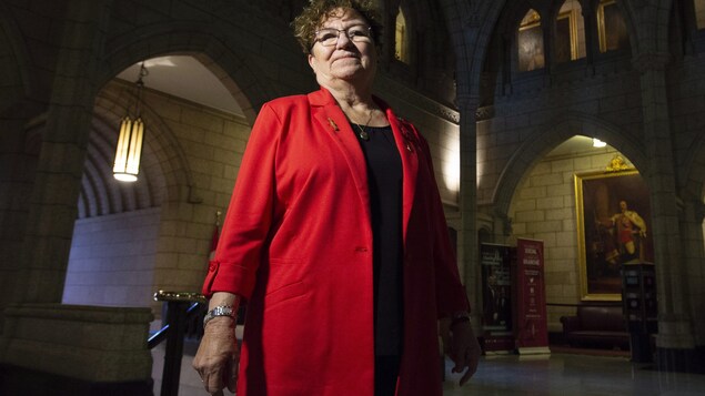 Yvonne Boyer debout, l'air confiant, dans le bâtiment du Parlement.