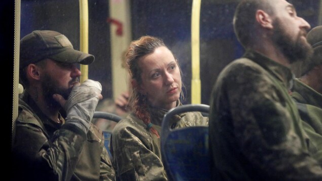 Deux hommes et une femme en habit de combat dans l'autobus. 