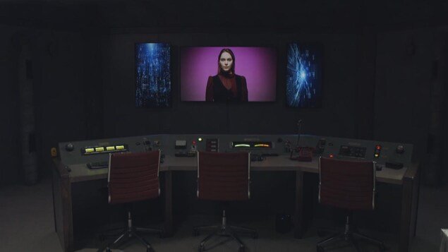 Un bunker futuriste où l'on aperçoit une femme androïde sur un écran face à une salle de commande.