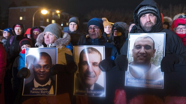Les citoyens tiennent des photos des victimes de la tuerie.