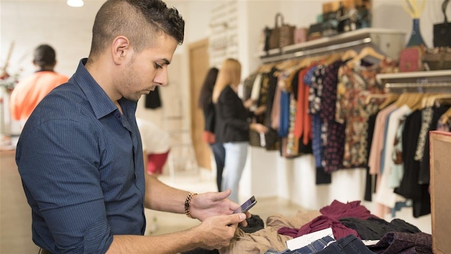 Un employé dans une boutique de vêtements placé devant des clientes qui magasinent