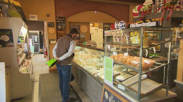 Un homme regarde l'étalage de fromages.