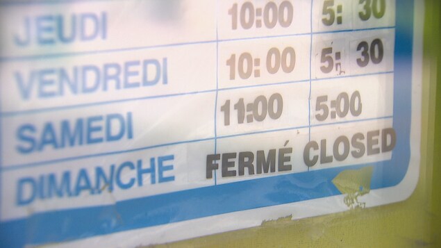 L'horaire d'un commerce posé dans une vitrine fermé le dimanche.