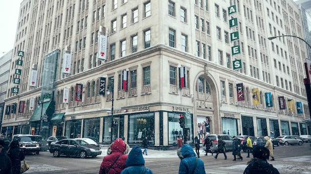 Le Complexe les Ailes avec les magasin Tommy Hilfigeret Sephora donnent sur la rue Sainte-Catherine, au centre-ville de Montréal. Des piétons marchent sous de fins flocons de neige.