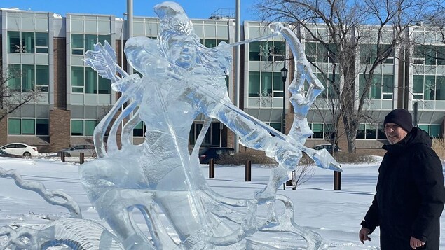 Le Winnipégois Bradley Froehlich se tient à côté de la sculpture sur glace d'un archer.