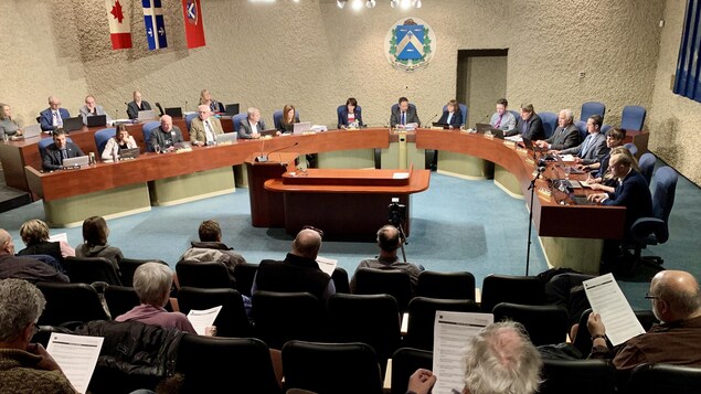 Élus attablés et le public à l'hôtel de ville.