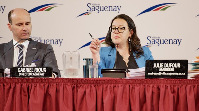 Gabriel Rioux et Julie Dufour sont assis derrière une table rouge.
