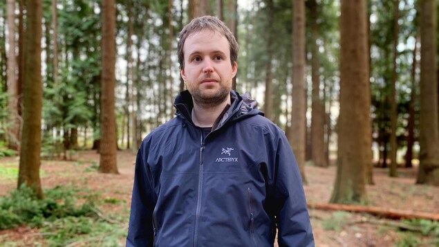 Guillaume Peterson St-Laurent dans une forêt regarde au loin.