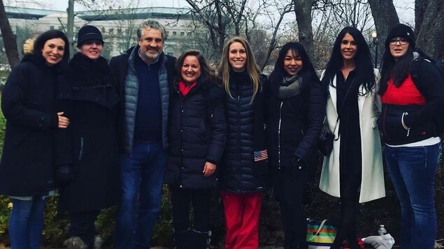 Huit personnes, côte à côte, sans masque, prennent la pose pour la caméra.