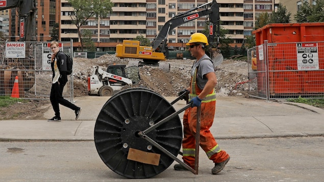 Un ouvrier du bâtiment passe devant un site de copropriété avec un rouleau de câble à Toronto, Ontario, Canada, le 8 octobre 2021