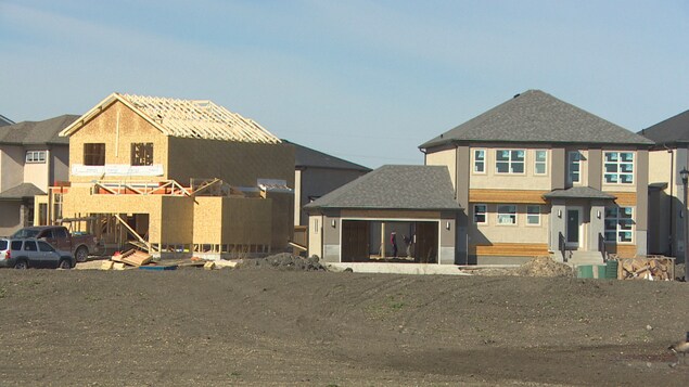 Deux maisons en construction, l'une est plus avancée que l'autre.