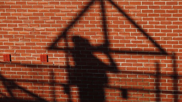 L'ombre d'un travailleur de la construction apparaît sur un mur de briques rouges.